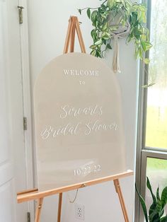 a welcome sign for the bride and groom in front of a potted green plant