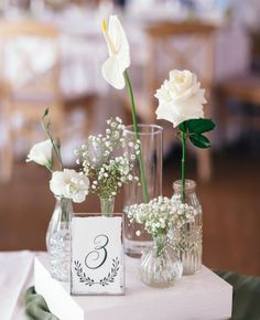 two vases with white flowers and baby's breath are sitting on a table