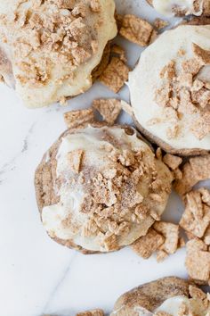 some cookies with white frosting and cinnamon sprinkles are on a marble surface