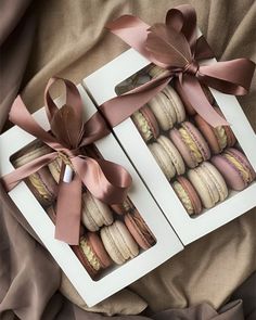 two boxes filled with macaroons wrapped in pink ribbon