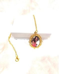 a white box with a gold plated necklace on it and a photo hanging from the front