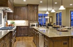 a large kitchen with wooden cabinets and marble counter tops