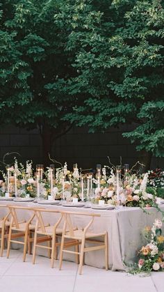 an outdoor table set up with flowers and candles