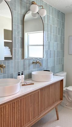 a bathroom with two sinks and mirrors on the wall next to each other in front of a toilet