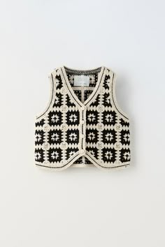 a black and white sweater vest hanging on a wall