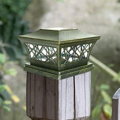 a bird is perched on the top of a lamp post in front of some trees