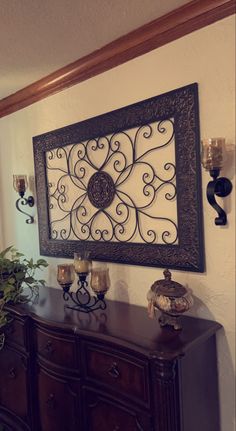 a wall hanging above a dresser with candles on it and a potted plant next to it