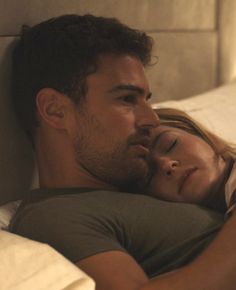 a man and woman laying in bed with their eyes close to each other as they cuddle