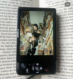 a cell phone sitting on top of a book with an image of a woman in the background