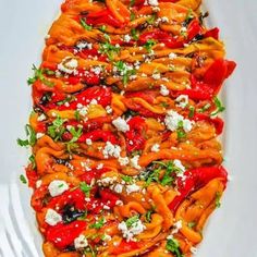 a white plate topped with lots of red and yellow food covered in fettuccine