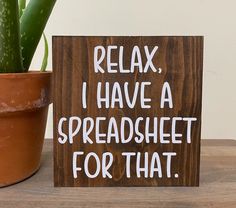 a wooden sign that says relax, i have a spreadsheet for that next to a potted plant