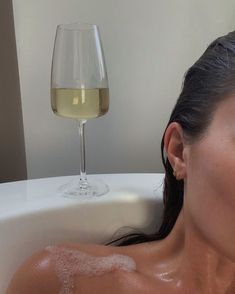 a woman sitting in a bathtub with a glass of wine next to her face