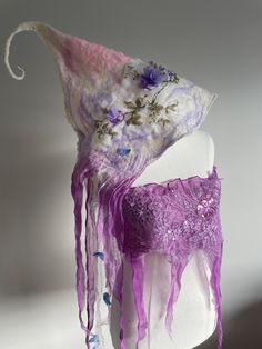 a white mannequin with purple fabric and flowers on it