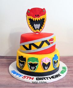 a three tiered cake decorated with an image of a monster head and other decorations