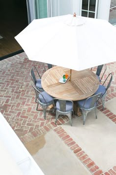 an overhead view of a patio table and chairs with an umbrella over the dining area