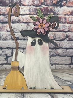 a white ghost holding a broom and wearing a black hat with pink flowers on it