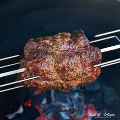 steak being cooked on the grill with tongs in it's mouth and some charcoal next to it