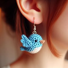 a close up of a pair of earrings with a blue bird on it's ear