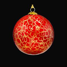 a red ornament with gold swirls on it's side, against a black background