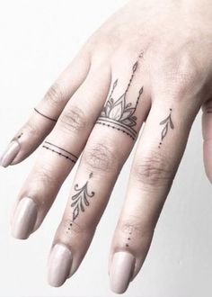 a woman's hand with two rings on it and a crown tattooed on the ring finger