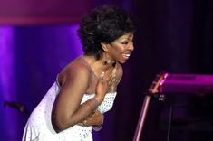 a woman in a white dress standing next to a microphone