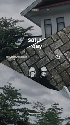 a pair of shoes sitting on top of a stone wall next to a building and trees