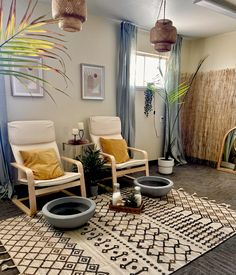 a living room with two chairs and a rug in front of a window that has plants on it