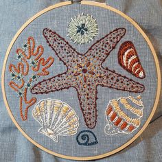 an embroidered starfish and seashells are featured in this embroidery pattern on denim fabric