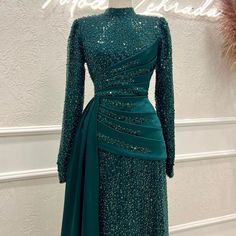 Step into the limelight with our stunning Emerald Lux Sequin Gown. This exquisite piece features a high neckline and long sleeves, providing an elegant silhouette that is both timeless and contemporary. The luxurious sequined fabric catches the light beautifully, ensuring youll shine at any special occasion.The gowns intricate draping across the bodice adds a touch of sophistication, perfectly complementing the classic, form-fitting design. A cascading sash accentuates the waist, creating a flattering and graceful aesthetic. This gown is more than just clothing it’s a statement of style and confidence.Ideal for galas, formal events, or any occasion where you want to leave a lasting impression, the Emerald Lux Sequin Gown combines glamour with comfort. The high-quality craftsmanship and att Gown With Long Sleeves, Sequined Fabric, Luxury Green, Evening Dress Long, Fashion Muslim, Islamic Clothing, Sequin Gown, Women Formals