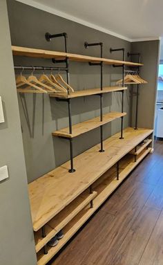 an empty walk in closet with wooden shelves and metal rails on the wall, next to a hardwood floor