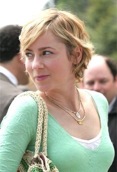 a woman in a green shirt is holding a purse and looking off to the side