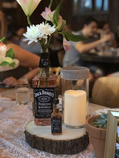 a table topped with a vase filled with flowers next to a lit candle and bottle