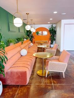 a living room filled with lots of furniture next to a green wall and potted plants