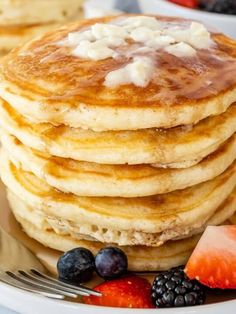 a stack of pancakes with syrup and fruit on the side, ready to be eaten