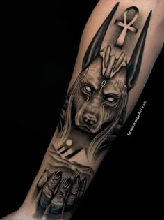 a man's arm with tattoos on it and an image of a demon holding a cross