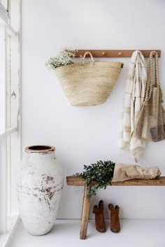 a white vase sitting on top of a wooden bench next to a wall mounted planter