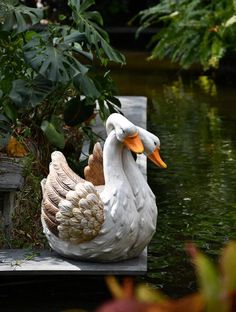 two white ducks sitting on top of a wooden dock next to a body of water