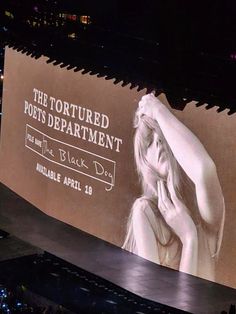 a large screen with the image of a woman covering her face in front of an audience