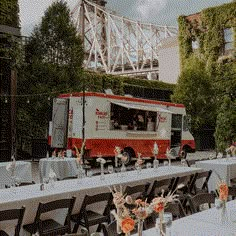 an orange and white food truck is parked in front of tables set up with chairs