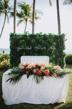 a table with flowers and greenery on it in front of the ocean at a tropical wedding