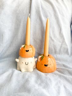 two candles sitting on top of each other in the shape of pumpkins with faces