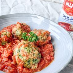 a white plate topped with meatballs covered in marinara sauce and broccoli