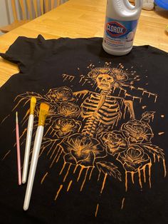 a t - shirt with a skeleton on it next to paintbrushes