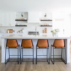 a kitchen island with four chairs in front of it and an open floor plan on the other side