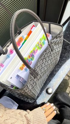 a woman holding a gray purse filled with books