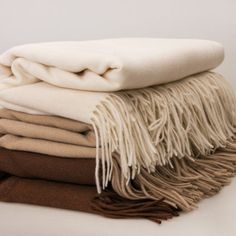 a stack of blankets folded on top of each other in different colors and sizes with fringes