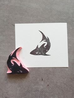 a piece of paper with a drawing of a shark on it next to a pink and black object