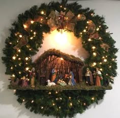 a nativity scene is hanging on the wall next to a christmas wreath with lights