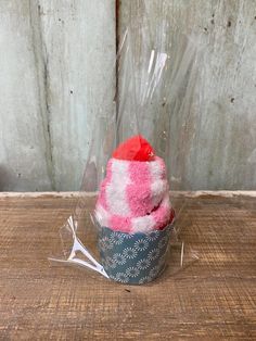 a cupcake wrapped in plastic sitting on top of a wooden table