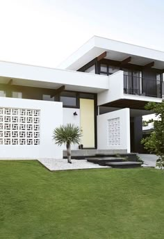 a modern house with white walls and green grass